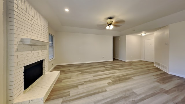 unfurnished living room featuring a brick fireplace, ceiling fan, and light hardwood / wood-style flooring