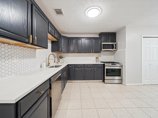 kitchen featuring sink, a textured ceiling, light tile patterned floors, stainless steel appliances, and decorative backsplash