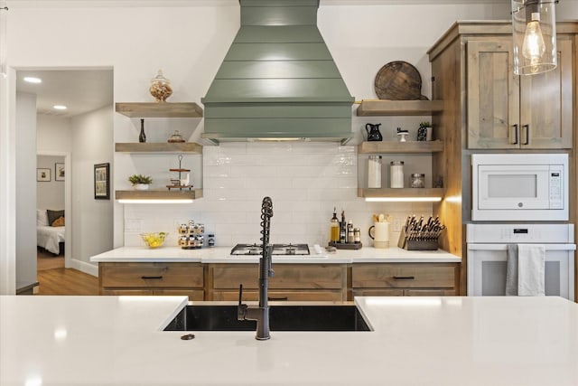 bar featuring decorative backsplash, white appliances, premium range hood, and hanging light fixtures