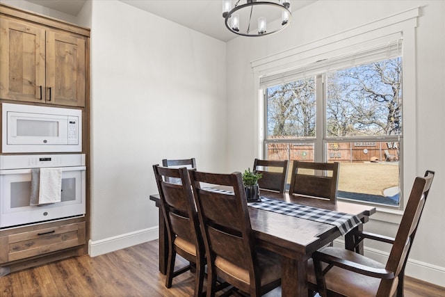 dining space with dark hardwood / wood-style floors and a notable chandelier