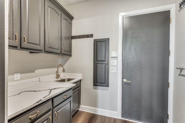 kitchen with dark hardwood / wood-style flooring, sink, light stone counters, and gray cabinets