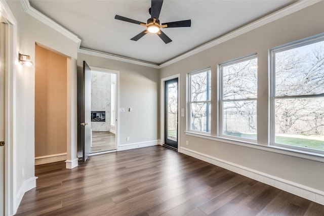 unfurnished room featuring crown molding, dark hardwood / wood-style floors, a fireplace, and ceiling fan