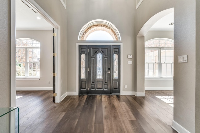 entrance foyer featuring dark hardwood / wood-style flooring, crown molding, and a towering ceiling