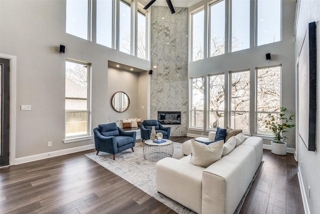 living room with a towering ceiling, dark hardwood / wood-style floors, and a premium fireplace