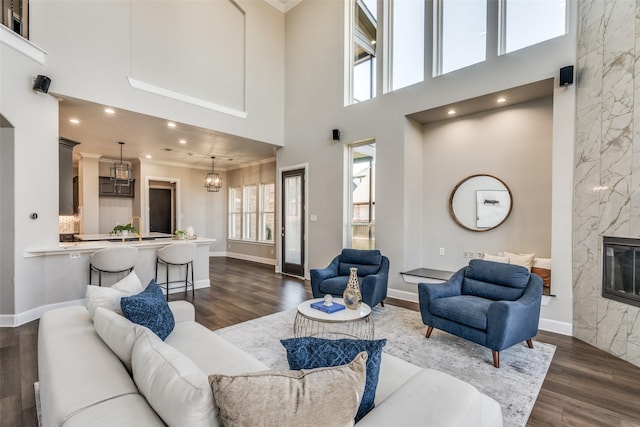 living room featuring crown molding, a premium fireplace, dark hardwood / wood-style flooring, and a high ceiling