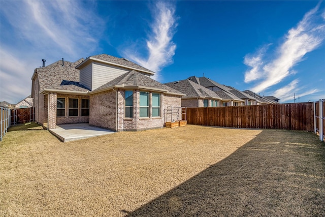 rear view of house featuring a patio area, a fenced backyard, a lawn, and brick siding