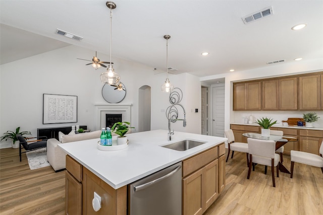 kitchen with sink, a center island with sink, light hardwood / wood-style flooring, dishwasher, and pendant lighting