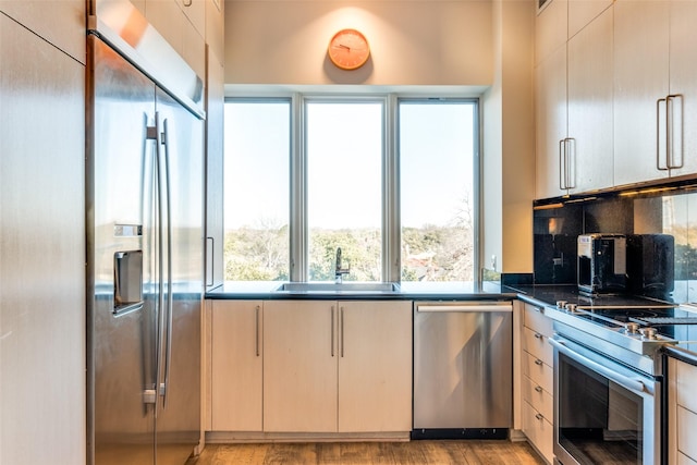 kitchen featuring stainless steel appliances, light hardwood / wood-style floors, sink, and decorative backsplash