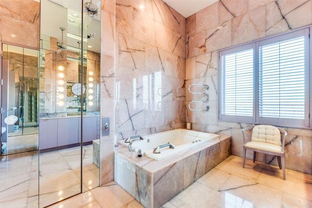 bathroom featuring vanity, tiled bath, and tile walls