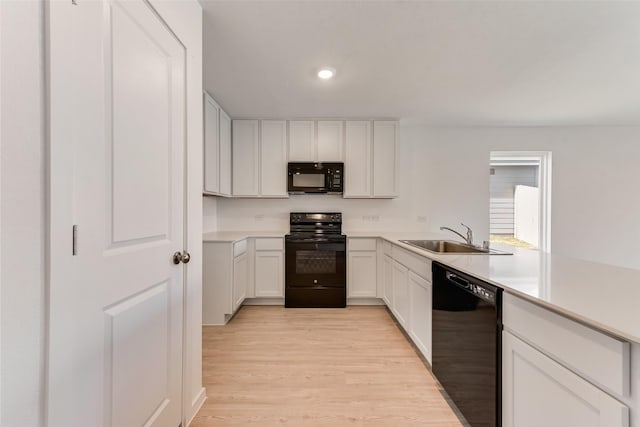 kitchen featuring black appliances, white cabinetry, sink, kitchen peninsula, and light hardwood / wood-style flooring