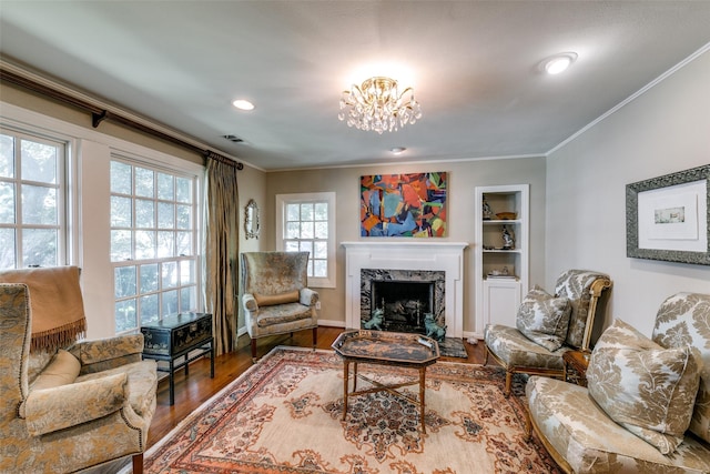 living room with an inviting chandelier, ornamental molding, a high end fireplace, and hardwood / wood-style floors