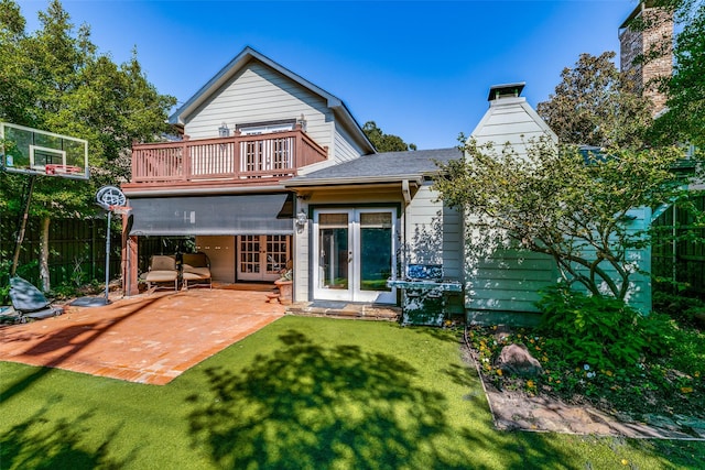 rear view of house featuring french doors, a balcony, a yard, and a patio