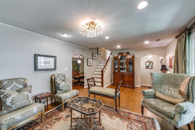 living room featuring crown molding, a chandelier, and light hardwood / wood-style floors