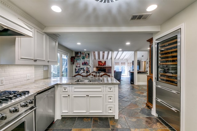 kitchen with sink, stainless steel appliances, wine cooler, white cabinets, and kitchen peninsula