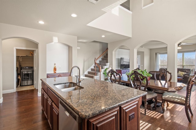 kitchen featuring sink, dishwasher, dark stone counters, a kitchen island with sink, and stove