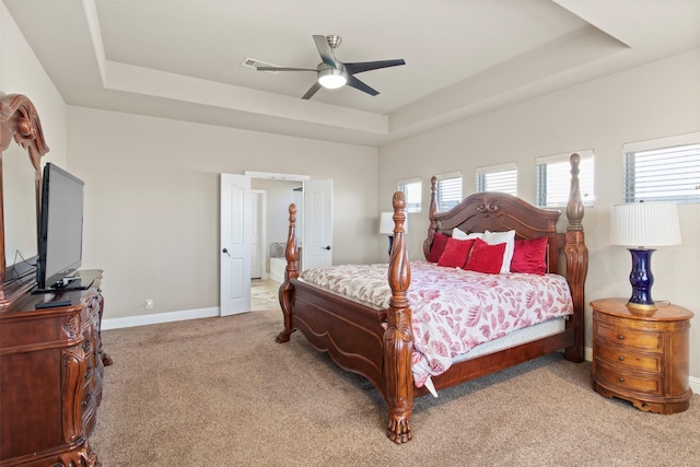 carpeted bedroom with ceiling fan and a tray ceiling