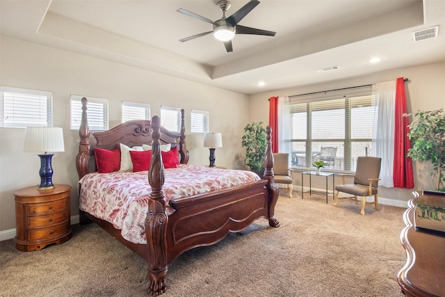 carpeted bedroom with ceiling fan and a tray ceiling