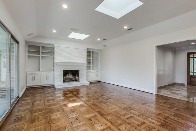 unfurnished living room with lofted ceiling with skylight, a brick fireplace, and built in shelves