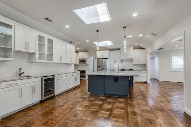 kitchen featuring wine cooler, white cabinetry, a center island, appliances with stainless steel finishes, and pendant lighting