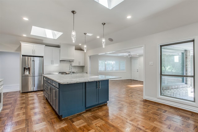 kitchen with a skylight, white cabinetry, parquet floors, and stainless steel fridge with ice dispenser