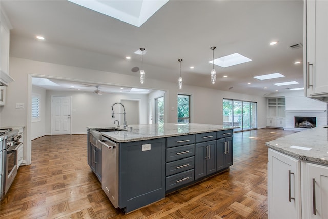 kitchen featuring sink, white cabinetry, hanging light fixtures, an island with sink, and stainless steel appliances