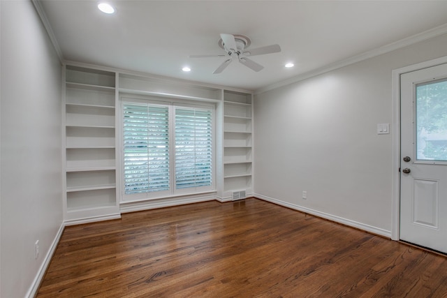 empty room with dark wood-type flooring, ceiling fan, crown molding, and built in shelves