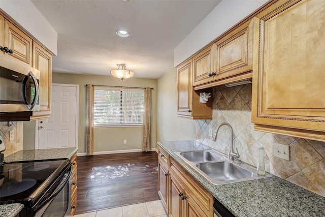 kitchen featuring sink, light tile patterned floors, backsplash, stainless steel appliances, and light stone countertops