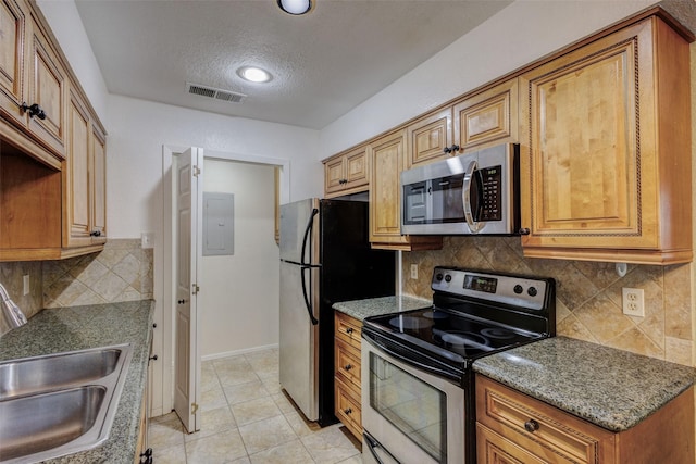 kitchen featuring sink, appliances with stainless steel finishes, dark stone countertops, backsplash, and light tile patterned flooring