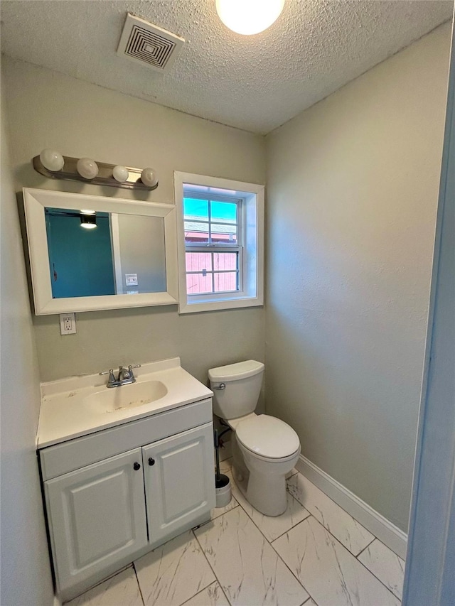 bathroom with vanity, a textured ceiling, and toilet