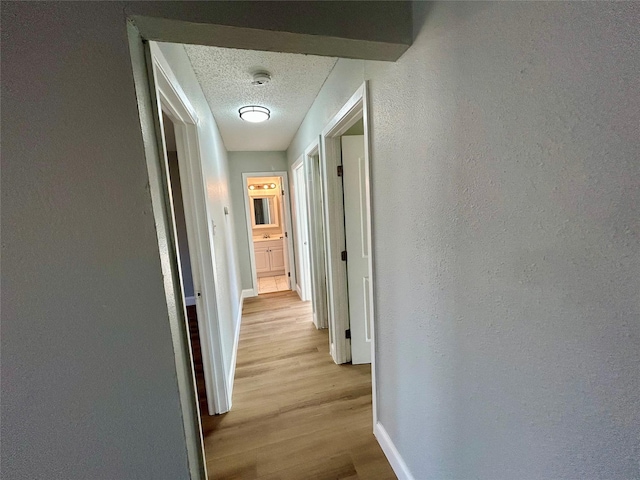 corridor featuring a textured ceiling and light wood-type flooring