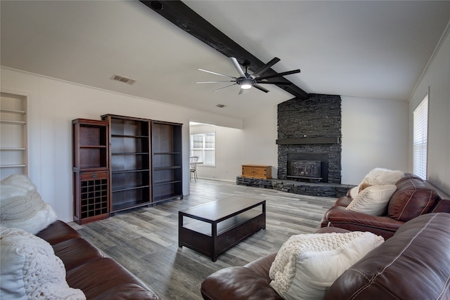 living room with a stone fireplace, lofted ceiling with beams, light hardwood / wood-style flooring, ceiling fan, and built in shelves