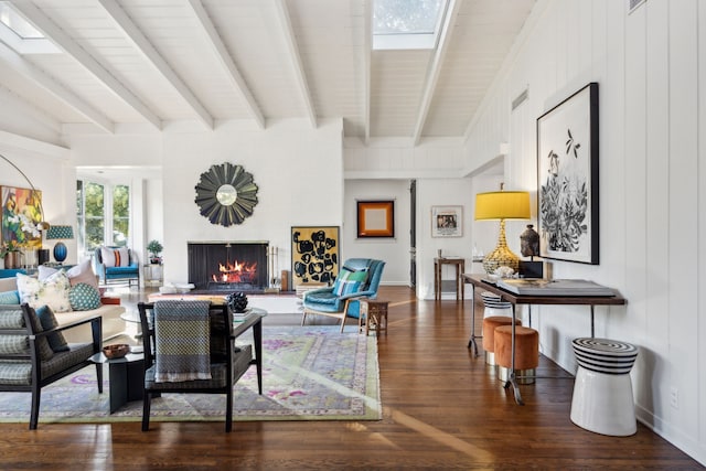 living area featuring a skylight, wood finished floors, baseboards, a lit fireplace, and beamed ceiling