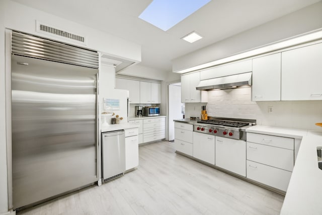 kitchen featuring extractor fan, stainless steel appliances, white cabinetry, light wood-style floors, and backsplash