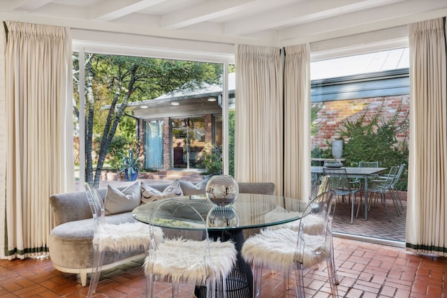 dining room with beamed ceiling and brick floor