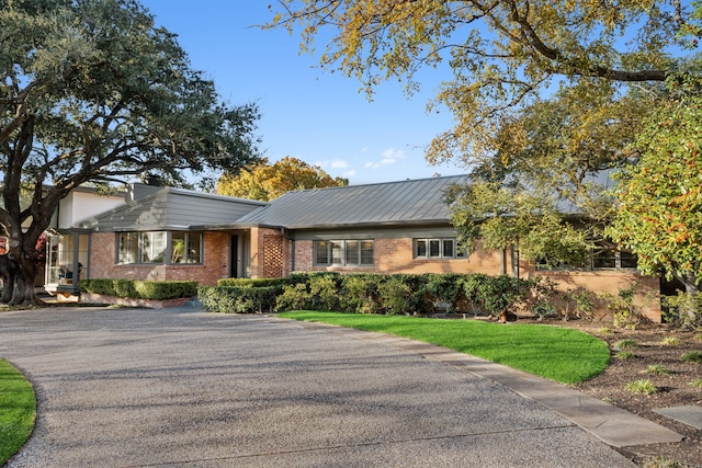 ranch-style home with metal roof and brick siding