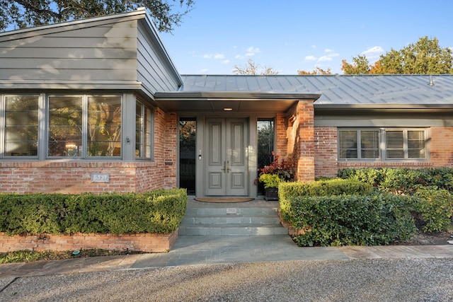 view of exterior entry featuring metal roof, brick siding, and a standing seam roof