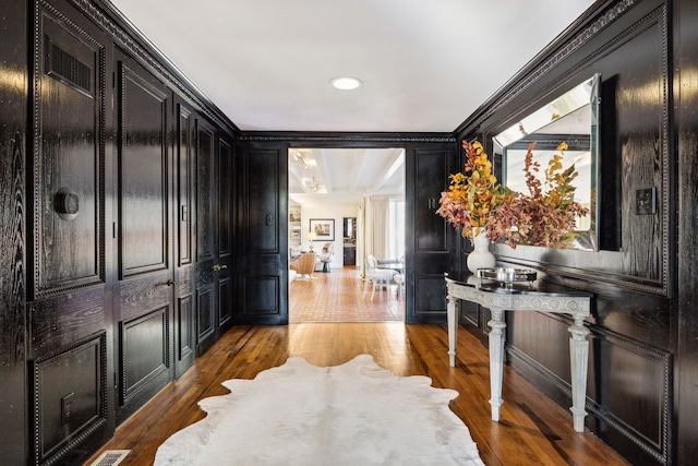 interior space with ornamental molding, wood finished floors, and a decorative wall