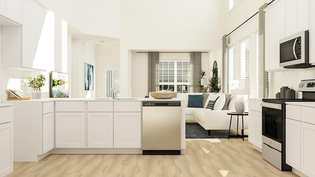 kitchen with stainless steel appliances, light wood-type flooring, and white cabinets