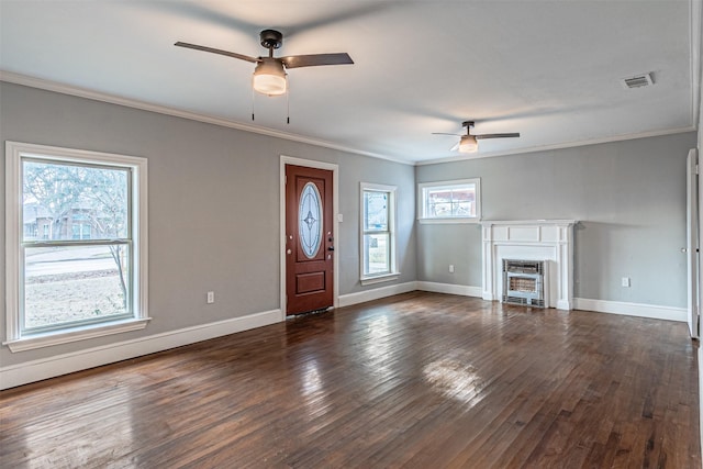 unfurnished living room featuring ornamental molding, a healthy amount of sunlight, dark wood-type flooring, and ceiling fan