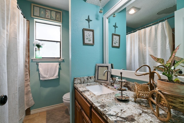 bathroom with tile patterned floors, toilet, vanity, and a textured ceiling