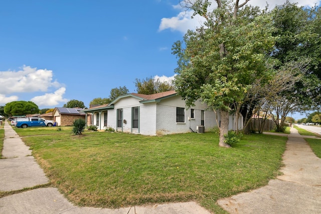 view of side of home featuring a lawn, cooling unit, and solar panels