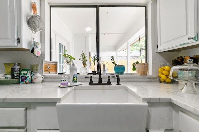 kitchen featuring white cabinetry, light stone countertops, and sink