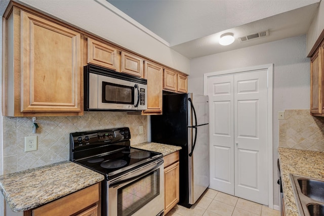 kitchen featuring light stone counters, stainless steel appliances, backsplash, and light tile patterned floors