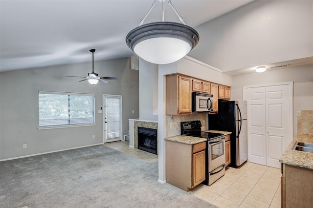 kitchen featuring lofted ceiling, appliances with stainless steel finishes, a high end fireplace, decorative backsplash, and light colored carpet