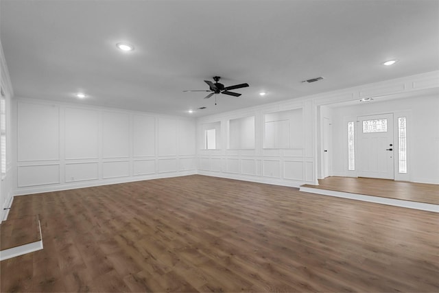 unfurnished living room featuring dark wood-style flooring, recessed lighting, visible vents, a decorative wall, and a ceiling fan