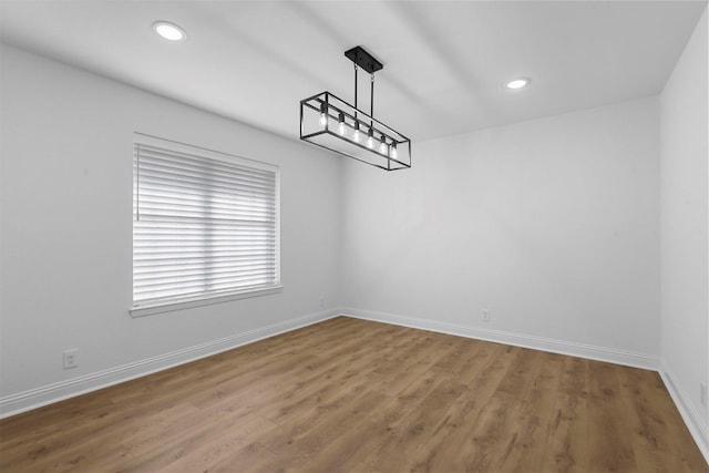 spare room with baseboards, wood finished floors, and recessed lighting