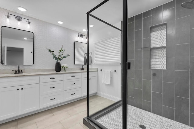 bathroom with double vanity, a stall shower, and a sink