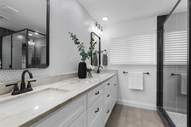 full bathroom featuring a stall shower, double vanity, a sink, and tile patterned floors