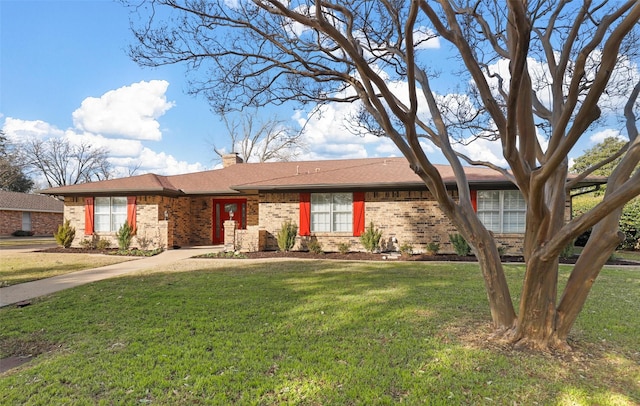 ranch-style house with brick siding, a chimney, and a front yard