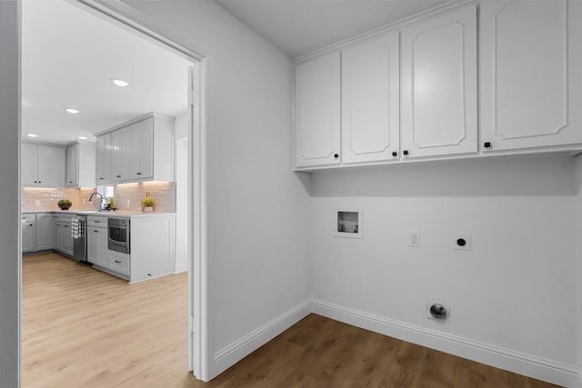 laundry room featuring hookup for a washing machine, cabinet space, light wood-style flooring, and electric dryer hookup